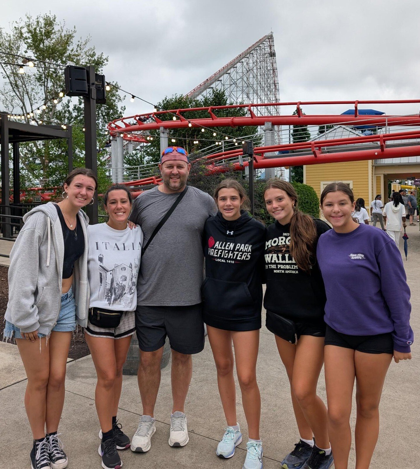 Renee and her family smile in front of a rollercoaster at Cedar Point.