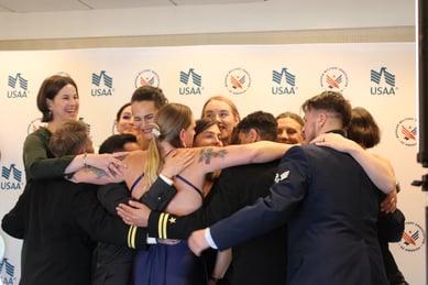 A big group hug is shown in front of a backdrop for a USAA x MMAA event.