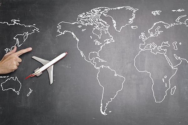 A miniature airplane sitting on top of a black and white map of the world.