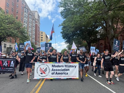 A large group of marchers in black t-shirts take to the streets during World Pride. They carry a banner forr the Modern Military Association of America.