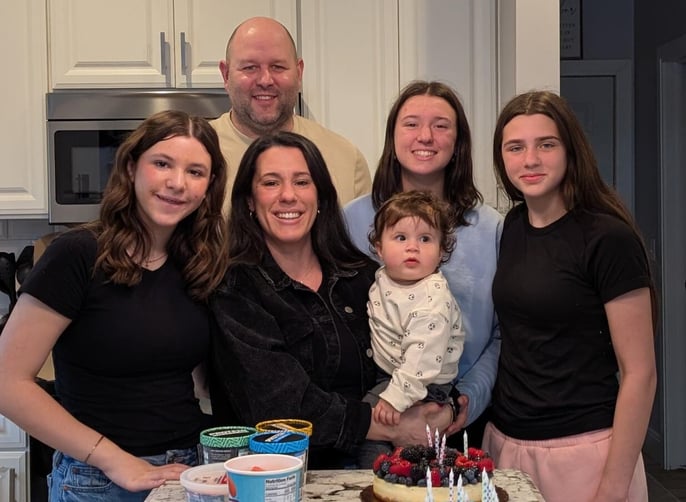 Renee and her family smile at the kitchen counter with cake and ice cream in front of them.