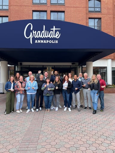 Populus Group Compass Award winners stand together outside the Graduate Annapolis hotel, smiling and holding up their compass awards.